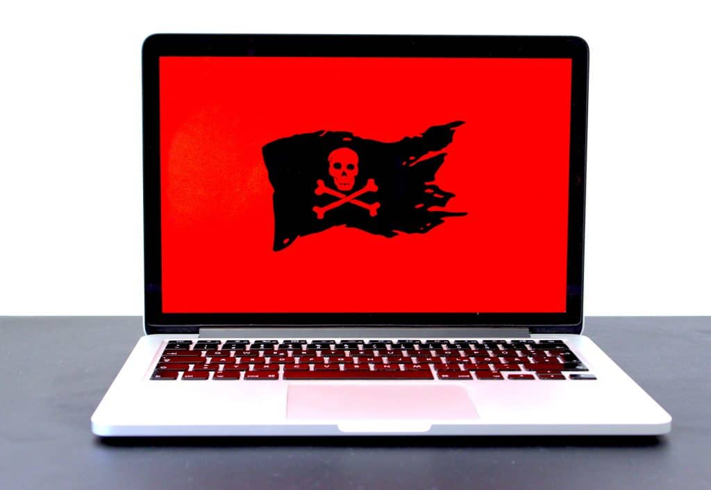 Laptop computer with red screen and skull and crossbones icon illustrates concept of computer problems.