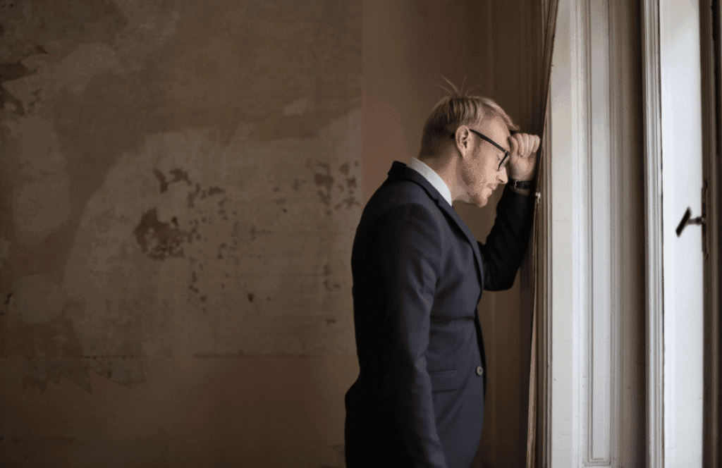Law firm owner in suit leans against a wall in distress after suffering an IT security incident.