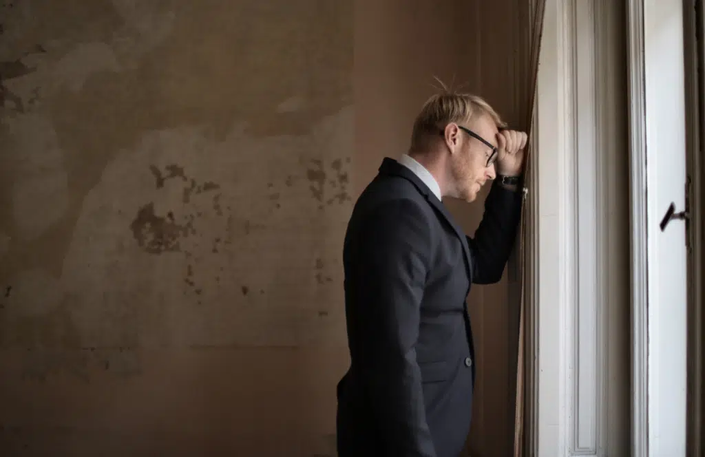 Law firm owner in suit leans against a wall in distress after suffering an IT security incident.