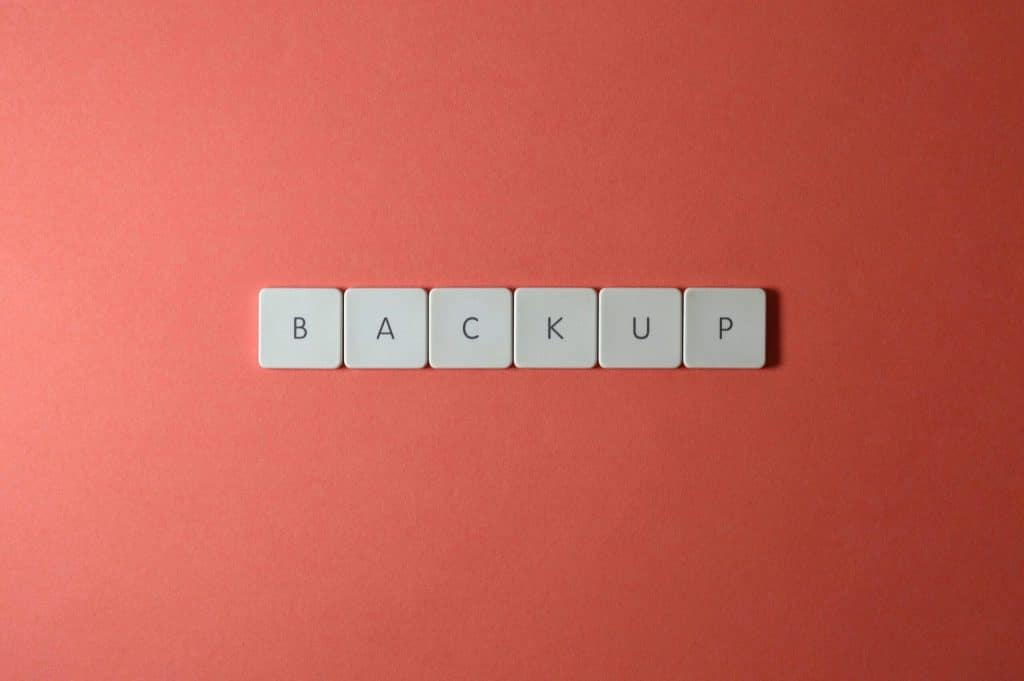 Free Close-up of keyboard keys spelling 'BACKUP' placed on a coral-colored surface. Stock Photo